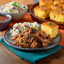 Seasoning-tossed pulled pork and cornbread slices on a plate with salad sides