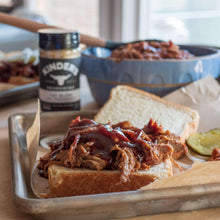 Kinder's The Blend seasoning salt jar on tray near pulled pork sandwiches