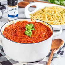 Red meat sauce in a white bowl with basil garnish and Kinder's Prime Rib Rub jar.