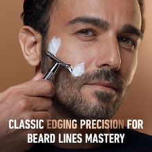 Chrome double edge safety razor held by hand with shaving lather on beard