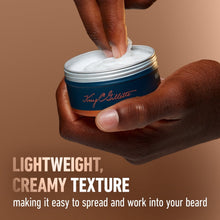 Beard softener balm jar held in hands with scooped creamy texture