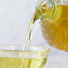Pouring canola oil into a glass bowl, with a clear bottle spout