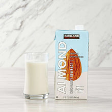 Almond milk carton with glass of light-colored almond milk