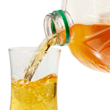 Apple juice bottle pouring golden liquid into a clear glass