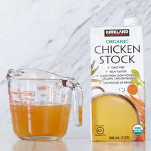 Organic chicken stock carton with measuring cup of broth