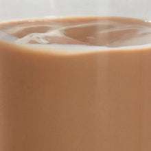 Pouring chocolate milk with creamy beige surface, close-up.