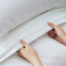 White sheet with elastic hem and hands adjusting the fabric