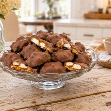 A glass dish piled with chocolate-coated caramel s'mores clusters