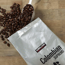 Coffee bag with whole beans and metal scoop on a wooden surface