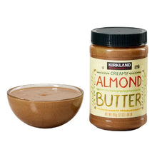Creamy almond butter jar beside a bowl filled with smooth almond butter
