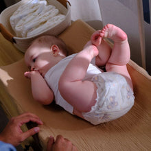 Baby lying down wearing a white diaper with animal prints