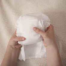 Hands holding a white diaper, back view with fastening tabs visible