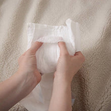 White diaper held open, with inner lining and tabs partially visible