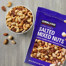 Salted mixed nuts in a bowl next to Kirkland Extra Fancy bag, loose nuts visible