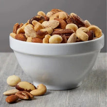 Bowl of salted mixed nuts, cashews and almonds with pieces scattered