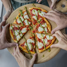 Basil pesto-topped pizza with white cheese and green basil garnish on board