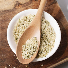 Bowl of shelled hemp hearts with wooden spoon on cutting board