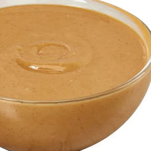 Creamy peanut butter surface in glass bowl, close-up