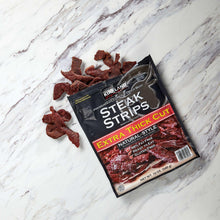 Extra thick steak strips bag with cured beef strips beside it on marble