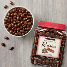 Chocolate raisin jar with red lid beside bowl of dark brown milk chocolate raisins