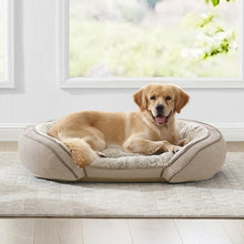 Beige orthopedic sloped pet bed with padded bolsters and circular base.