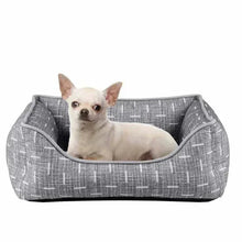 Gray pet bed with wide sides and curved rim opening, small dog resting inside