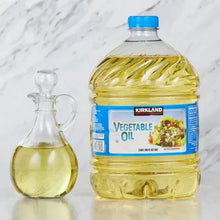 Vegetable oil bottle with blue cap and small glass cruet filled with golden oil