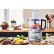 KitchenAid 7-cup food processor with clear bowl holding fruit, silver base