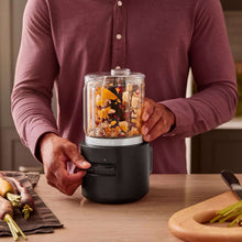 Cordless food chopper with clear bowl, black base, and chopped ingredients inside