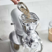 Grain mill hopper spilling dried grains into grinding chamber