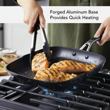 Black nonstick skillet cooking on a gas stove with two hand grips