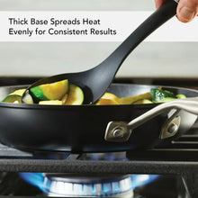 Black nonstick fry pan with thick base, spatula lifting vegetables