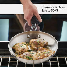 Stainless steel fry pan on an oven rack, filled with browned meat and herbs