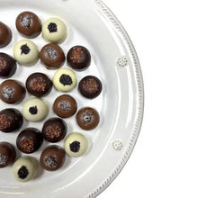 Chocolate truffles on white plate: dark and cream centers with speckled topping