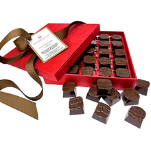 Gift box with ribbon and label containing dark chocolate truffles on tray