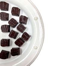 Dark chocolate truffles arranged on a white round plate