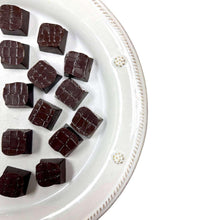 Dark chocolate truffles on white tray, cube-like square pieces