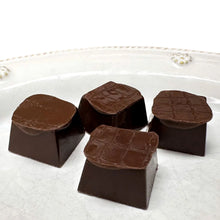 Dark chocolate truffles on a white plate, three pieces in view