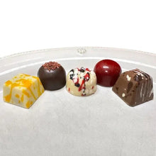 Assorted chocolate truffles on white plate: dark, red, and patterned pieces
