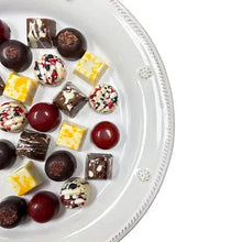 Assorted chocolate truffles on white plate, close-up of bite-size pieces