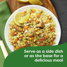 Bowl of chicken broccoli rice and pasta mix with lemon slice and herbs.