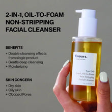 Hand holding 2-in-1 oil-to-foam facial cleanser bottle with pump, honey-gold liquid