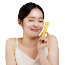 Yellow cream patch tube held near face with cream dot on cheek