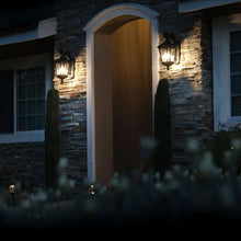 Outdoor wall lantern lights flanking an entry arch, black frames, warm glow