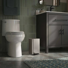 Stainless step trash can next to bathroom fixtures, lid closed with pedal visible.