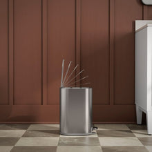 Stainless steel step trash can with open top lid and items inside