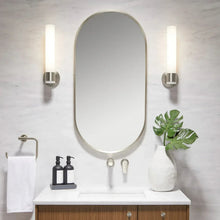 Wall-mounted capsule mirror with thin gray frame and rounded top