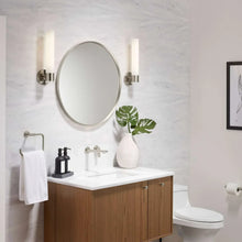Round framed bathroom mirror above a white vanity