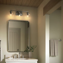 Three-light wall sconce over mirror with clear globe glass shades and dark metal frame