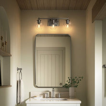 Three-light wall sconce over mirror with clear globe glass shades and dark metal frame